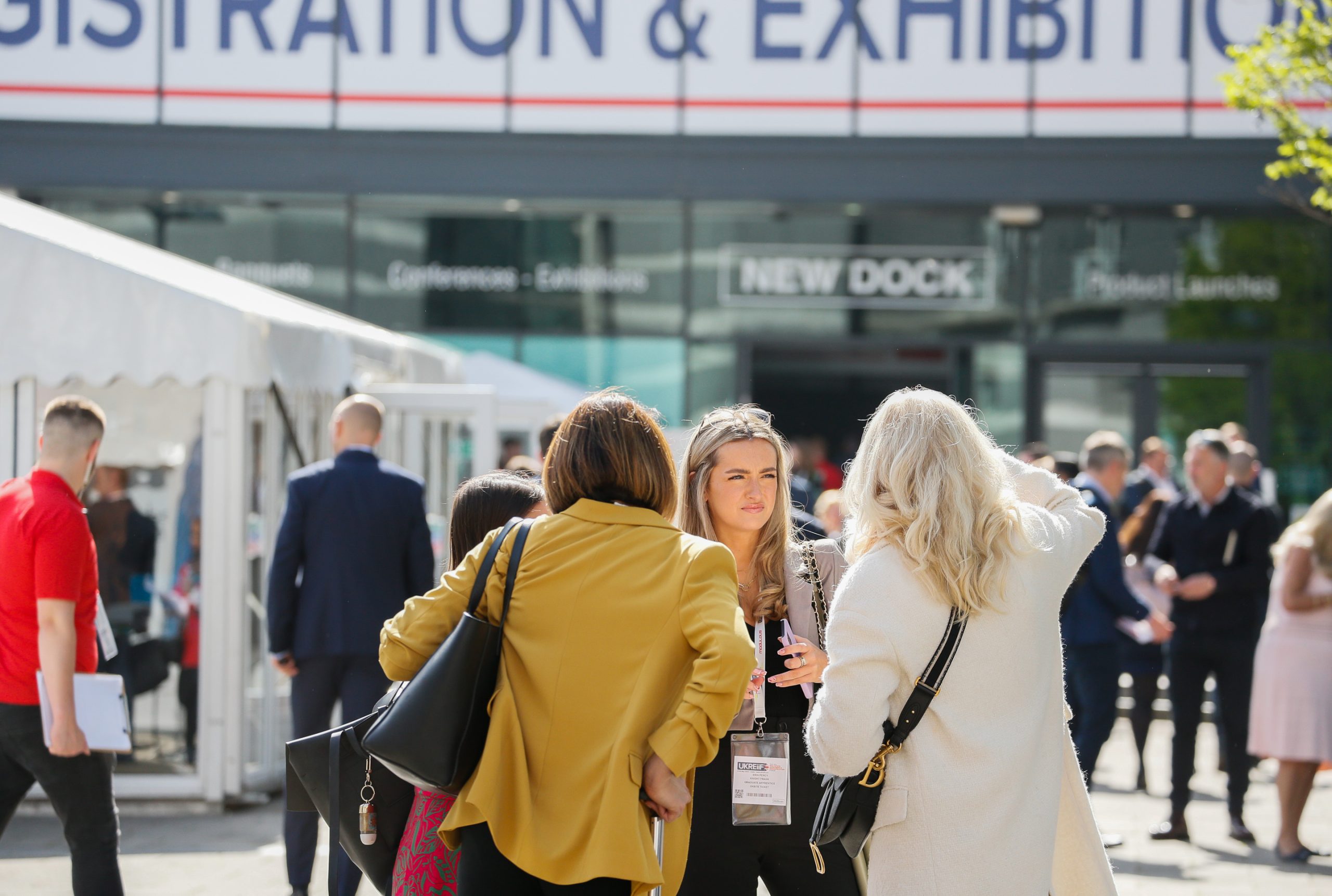 Three people at a conference outside chatting to each other