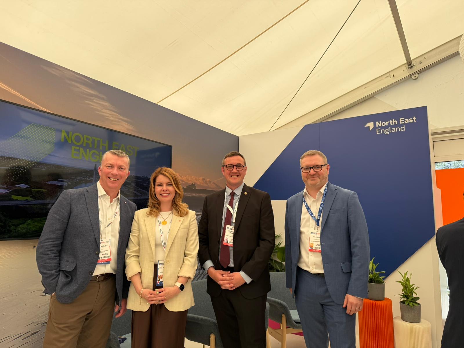 Panelists at UKREiiF posing on the North East England stage after investment prospectus launch. They are all smiling to camera.